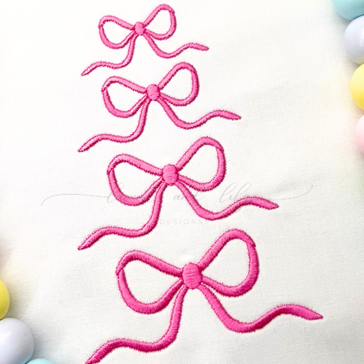 Four pink embroidered bows on a white background
